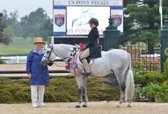 a woman standing next to a white horse