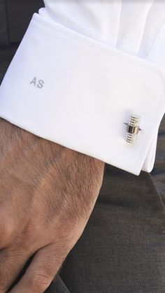 a man's hand wearing a white dress shirt and cufflinks with the number 45 on it