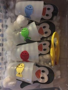 there are many penguin cups in the box with toothbrushes and other things inside