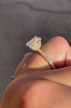 a woman's hand holding a yellow and white diamond ring