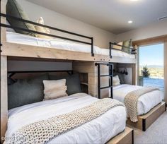 two bunk beds are in the middle of a room with a large window overlooking water