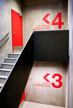 stairs leading up to an entrance with red door and white lettering on the wall that says wayfinding modern info graphics and navigation