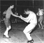 an old photo of two men on skateboards in the middle of a dance floor