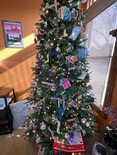 a decorated christmas tree in the corner of a living room with pictures and ornaments on it