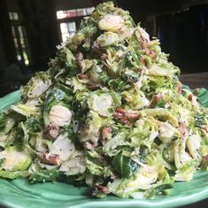 a green plate topped with a pile of lettuce covered in dressing and toppings