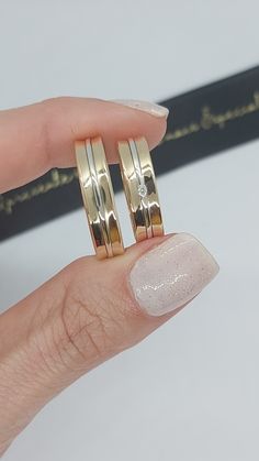 a woman's hand holding two gold rings