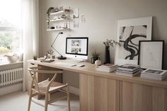 a desk with two computer monitors on top of it next to a chair and window