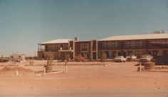 a large building with cars parked in front of it and dirt area around the buildings