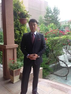 a man in a suit and tie standing on a patio