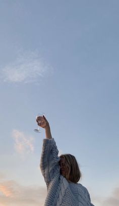 a woman holding a wine glass up in the air