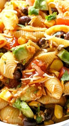 pasta salad with black olives, tomatoes, peppers and cheese in a white bowl