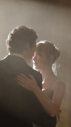 a bride and groom embracing each other in front of the light coming from behind them