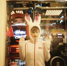 a woman in bunny ears is posing for the camera with her hands up to her head