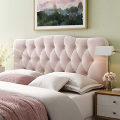 a pink headboard in a bedroom next to a night stand with flowers on it