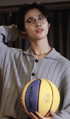 a woman holding a basketball in her right hand and wearing glasses on top of her head