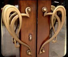 two wooden doors with metal handles on each side and heart shaped locks at the top