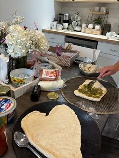 two heart shaped pizzas sitting on top of pans in a kitchen next to flowers