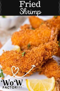 fried shrimp on a white plate with lemon wedges