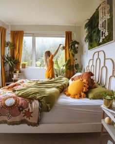 a woman standing on top of a bed in a bedroom next to a large window