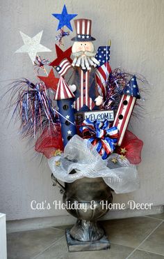 a patriotic arrangement in a pot on the ground with stars and ribbons around it that says welcome home decor