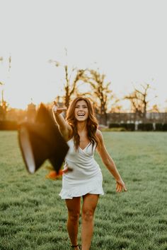 a woman in a white dress is holding an umbrella and laughing while standing in the grass