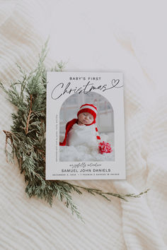 a baby's first christmas book laying on top of a white blanket next to a plant