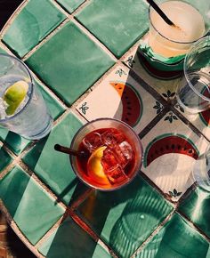 three glasses of alcohol sit on a tiled table