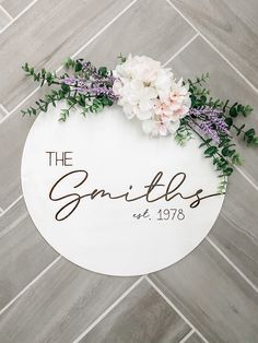 a sign that says the smiths with flowers and greenery around it on a tile floor