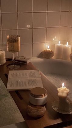 a candle is lit next to an open book on a table with candles in the background