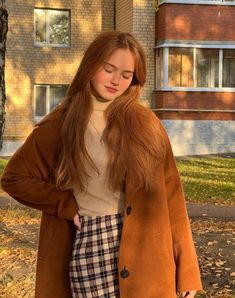 a girl with long red hair wearing a brown coat