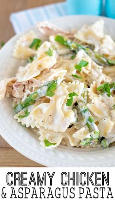 creamy chicken and asparagus pasta on a white plate with a blue cup in the background