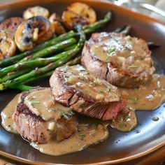 steak with mushroom gravy and asparagus on a brown plate next to potatoes