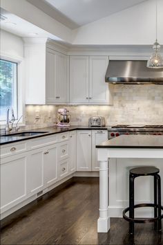 a large kitchen with white cabinets and black counter tops, an island in the middle