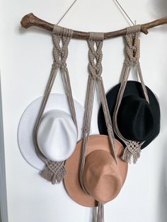 three hats hanging on a wall with rope