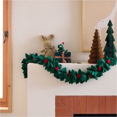 a christmas mantle with decorations on it and a stuffed animal in the corner, next to a fireplace