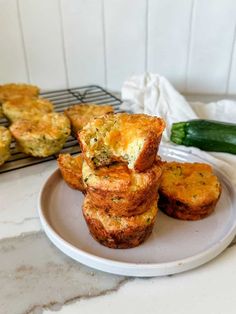 several muffins stacked on top of each other on a plate next to a cucumber