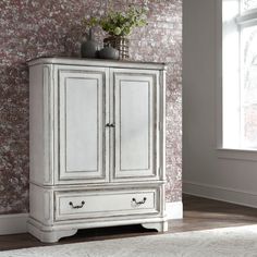 an antique white armoire with drawers in front of a brick wallpapered room