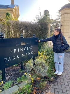 a woman pointing at the princess park manor sign