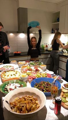 a group of people standing around a table filled with plates and bowls full of food