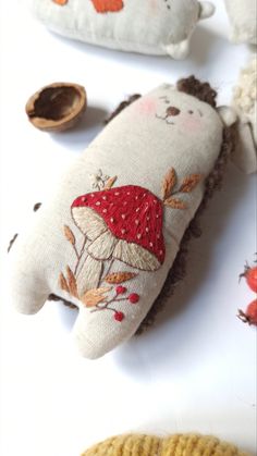 two stuffed animals are sitting next to each other on a white surface, one is wearing a red hat