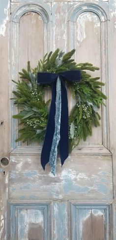 a wreath on the front door of an old building with blue ribbon hanging from it