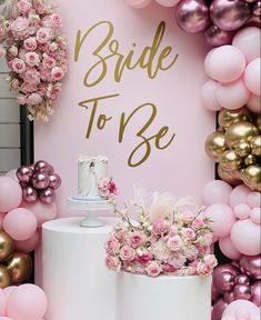 a pink and gold bridal to be sign next to balloons