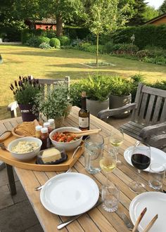 a wooden table topped with plates and glasses of wine