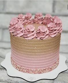 a cake with pink frosting flowers on top sitting on a white plate next to a brick wall