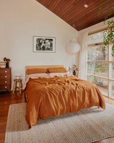 a bed sitting in a bedroom next to a window with a plant on top of it