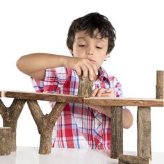 a young boy sitting at a wooden bench with his hands on the top of it