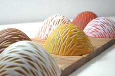 four different colored vases sitting on top of a wooden cutting board next to each other