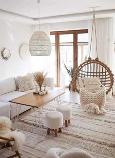 the living room is decorated in white and neutral colors with hanging chairs, rugs, ottomans