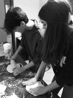 two people are making dough on a table