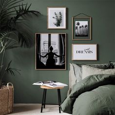 a bedroom with green walls and pictures hanging on the wall above it, along with a small side table